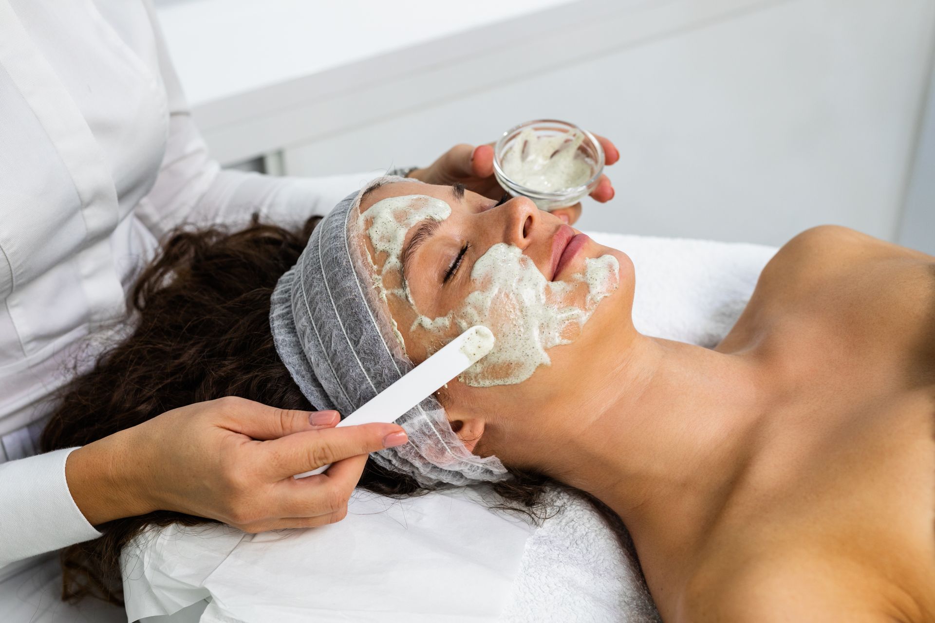 A woman is receiving a natural green peel facial mask with rejuvenating effects