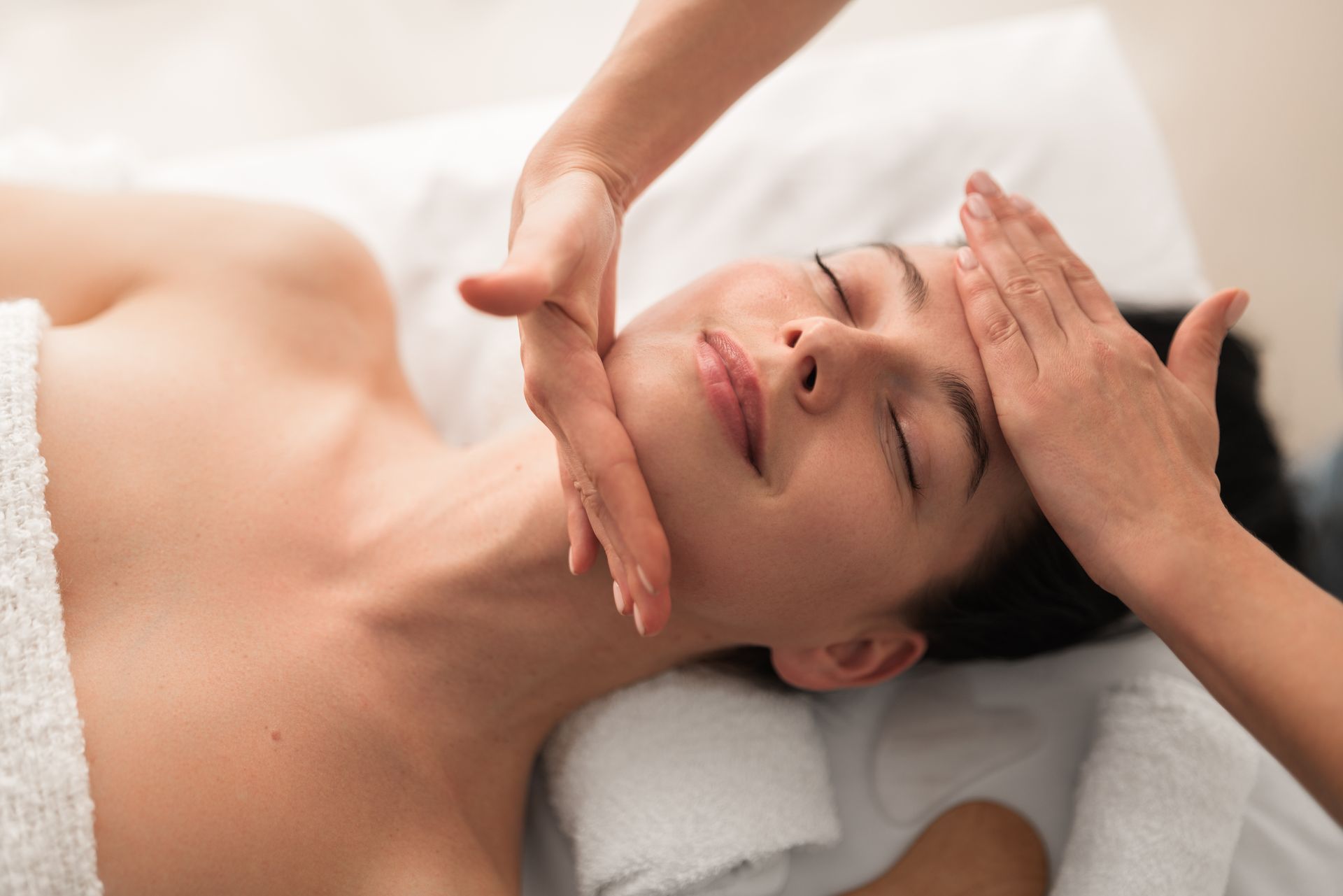 Woman receiving a relaxing facial head massage at a spa.
