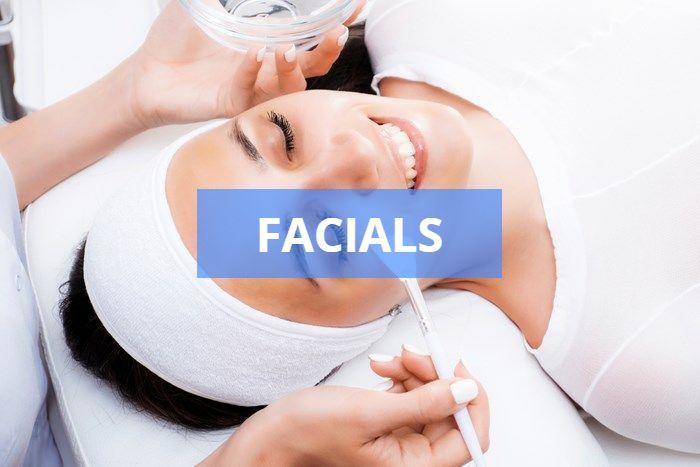 Woman receiving facial treatment at a spa; a person is applying product to her face. 