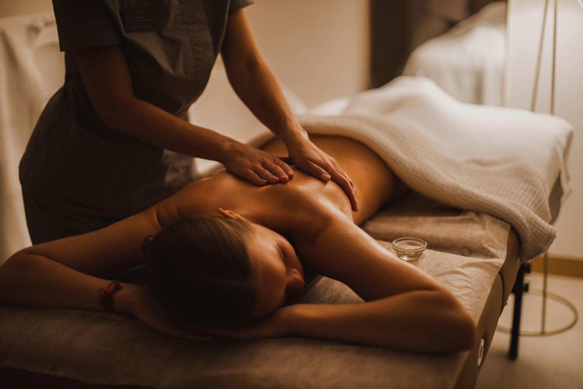 Professional massage therapist performing therapeutic back massage in clinic 