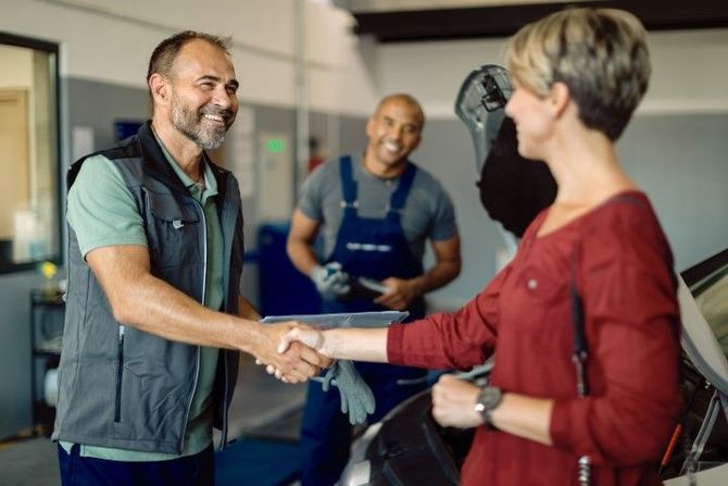 Two people shaking hands in a gym, with another person smiling in the background.