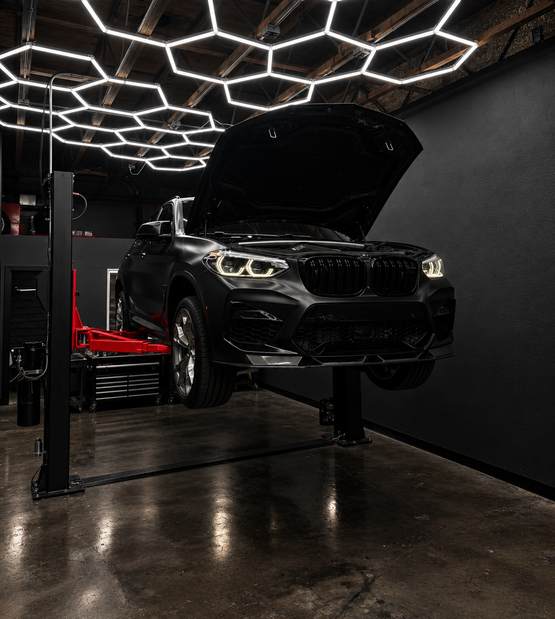 BMW SUV on a lift under hexagon shop lights at CD Autoworks