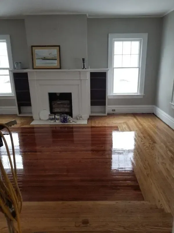 Living room with refinished hardwood floors, fireplace, and built-in shelves. Windows on either side.