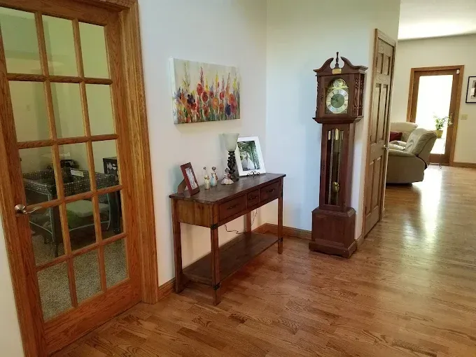 Wooden entryway with a console table, grandfather clock, and a glass-paned door.
