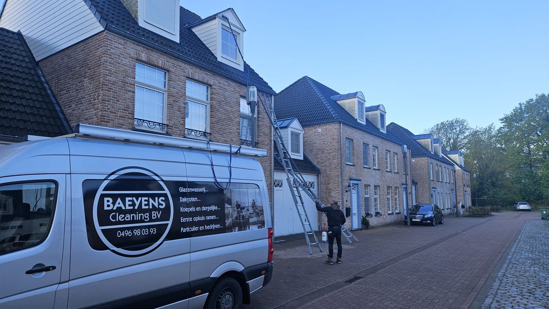 A white van is parked in front of a row of houses.