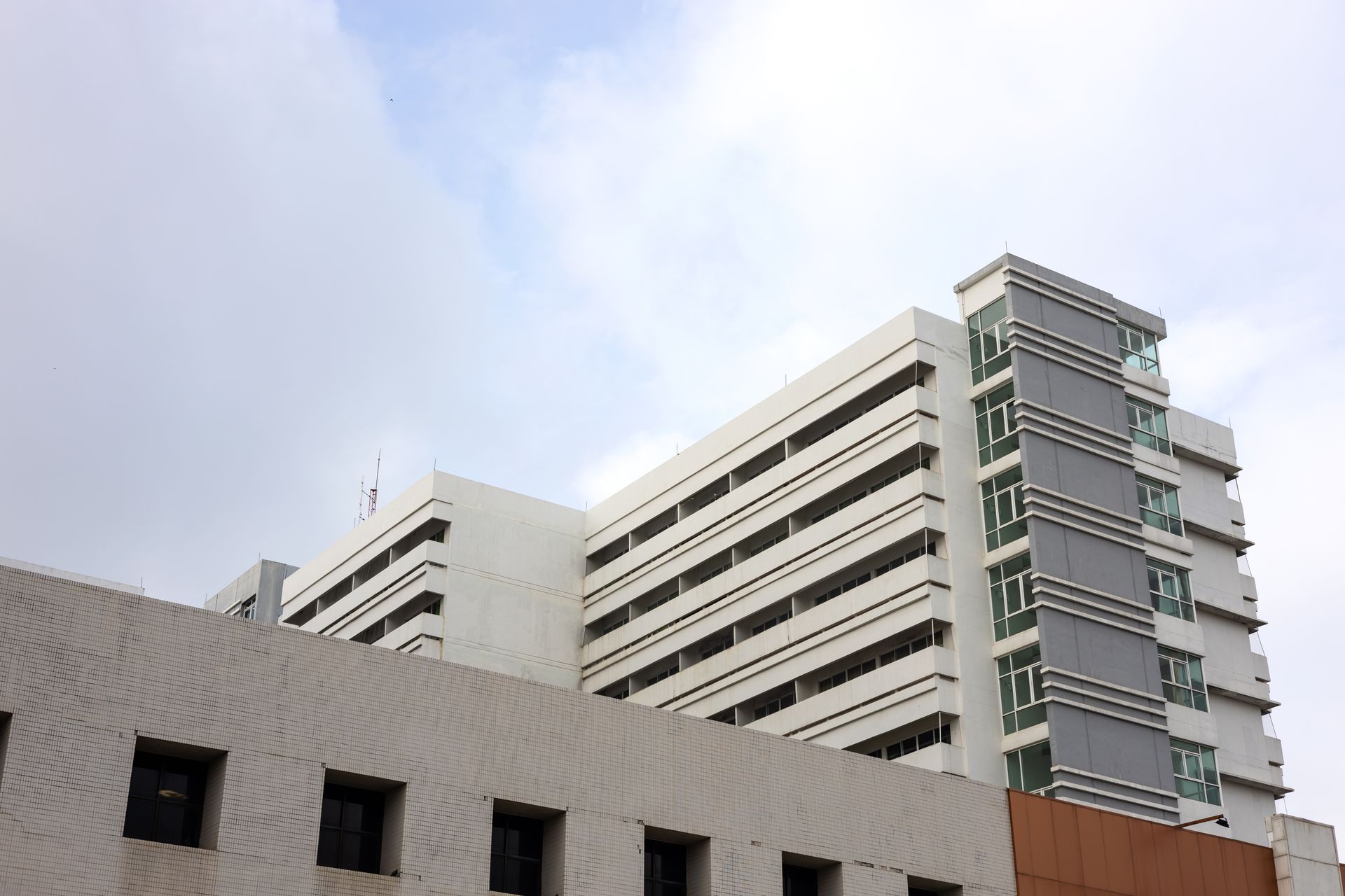 Een groot gebouw met veel ramen tegen een bewolkte lucht.