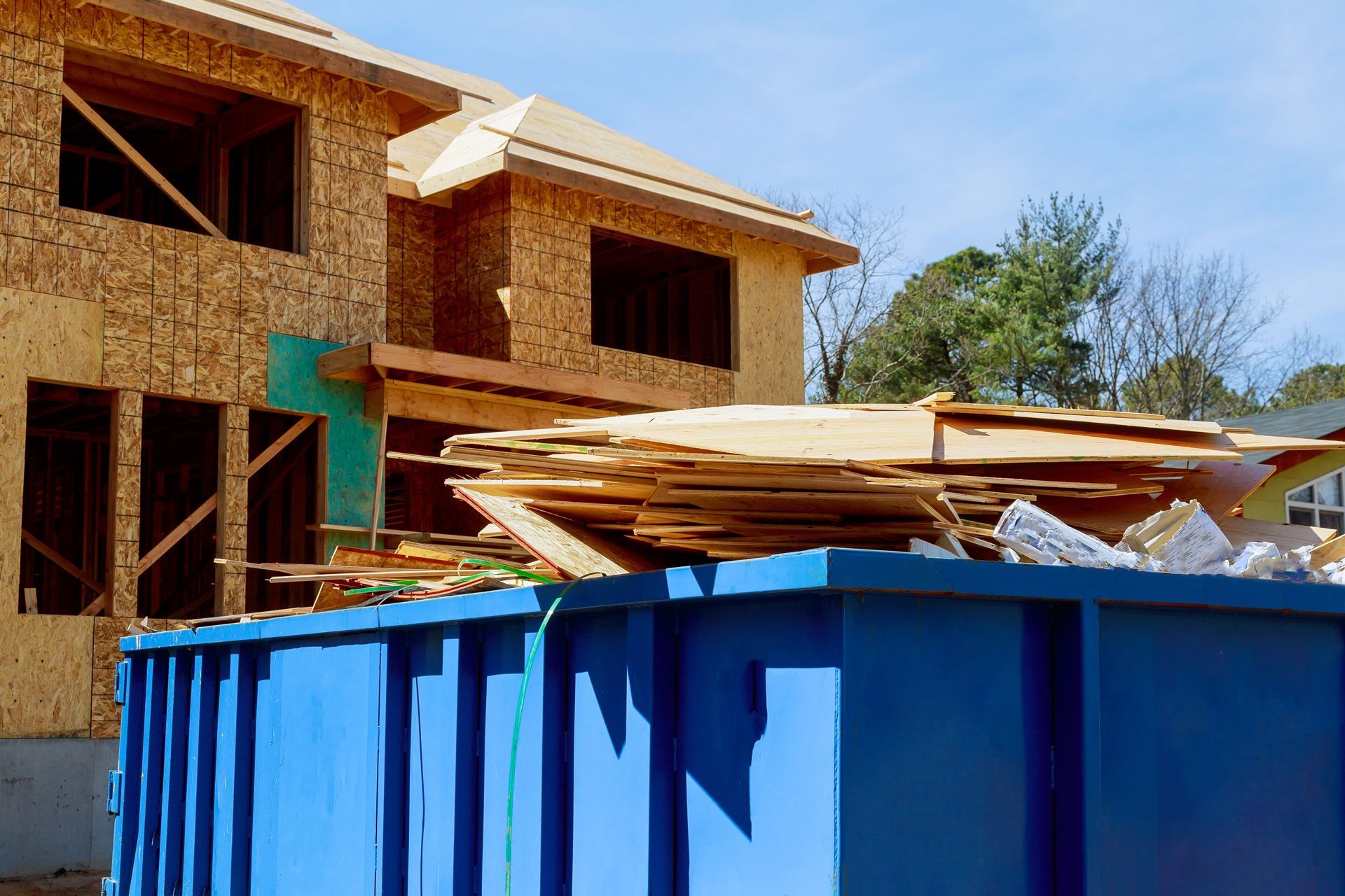 A Blue Dumpster is Sitting in Front of a House Under Construction