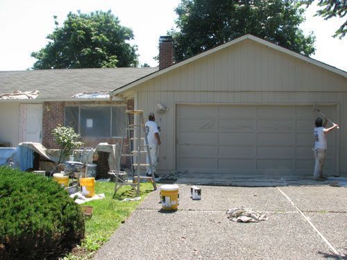 Two men are painting the side of a house
