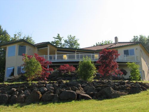 A large house sits on top of a rocky hillside