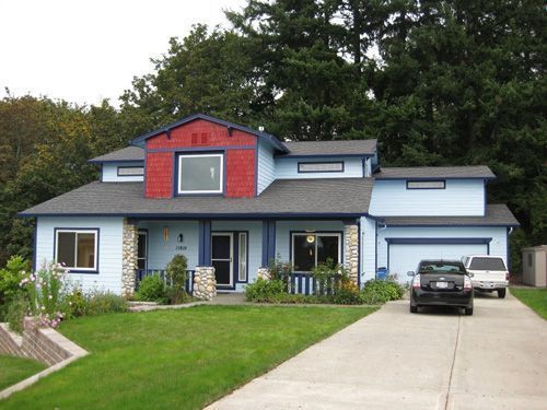 A blue house with a red roof and a car parked in front of it