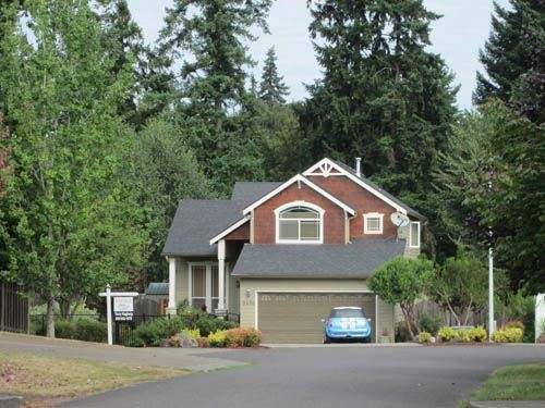 A blue car is parked in front of a red house