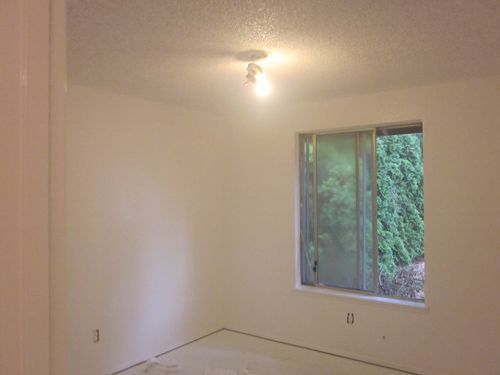An empty room with a window and a light on the ceiling.