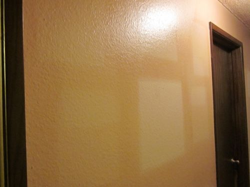 A hallway with a door and a light on the wall.