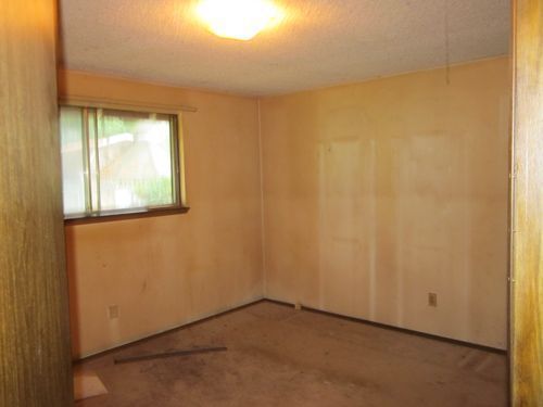 An empty room with a window and a light on the ceiling.