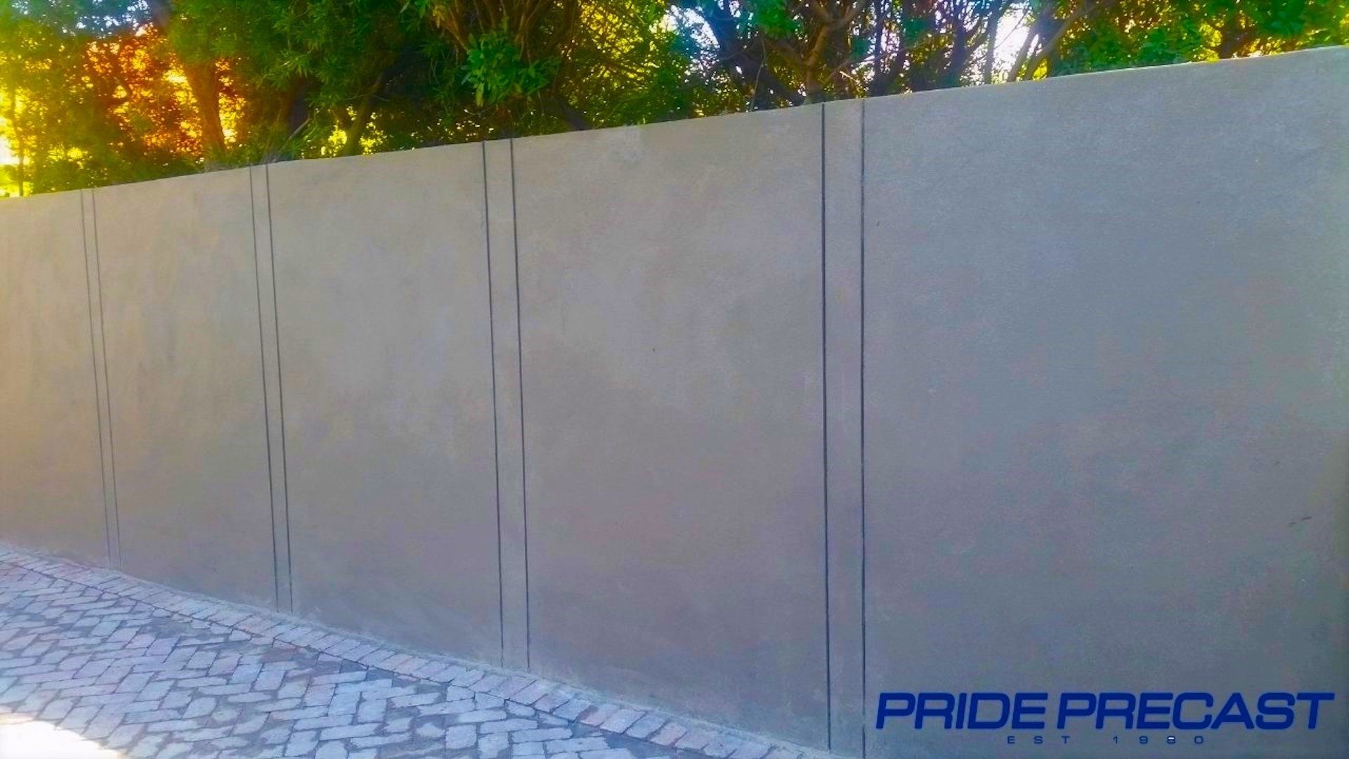 A concrete fence is sitting next to a cobblestone street.