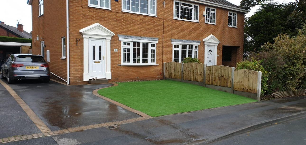 Brick house with white doors and windows, driveway, and a small green lawn by the street.