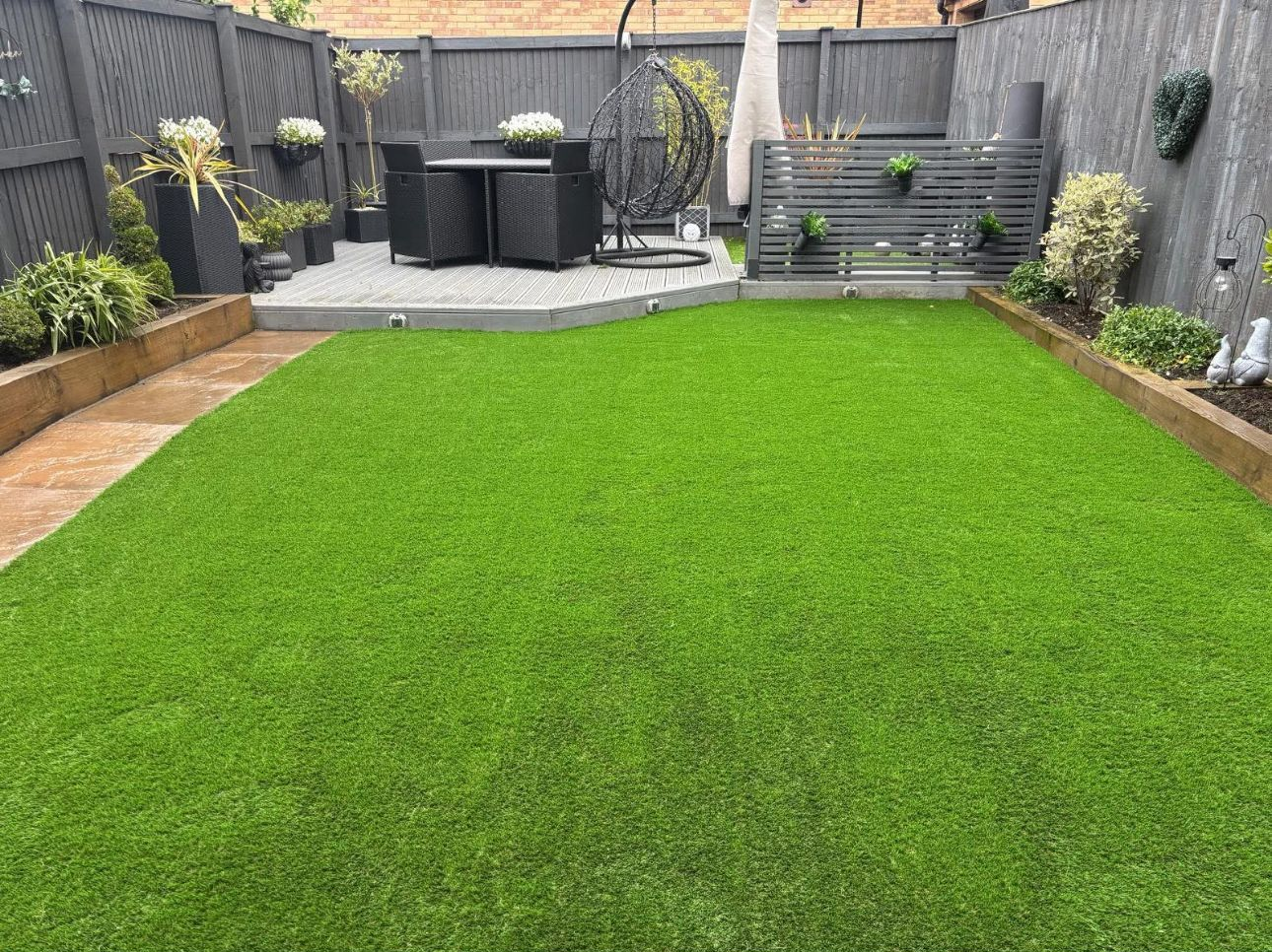 Backyard with bright green lawn, patio seating, and wooden fence in a modern garden