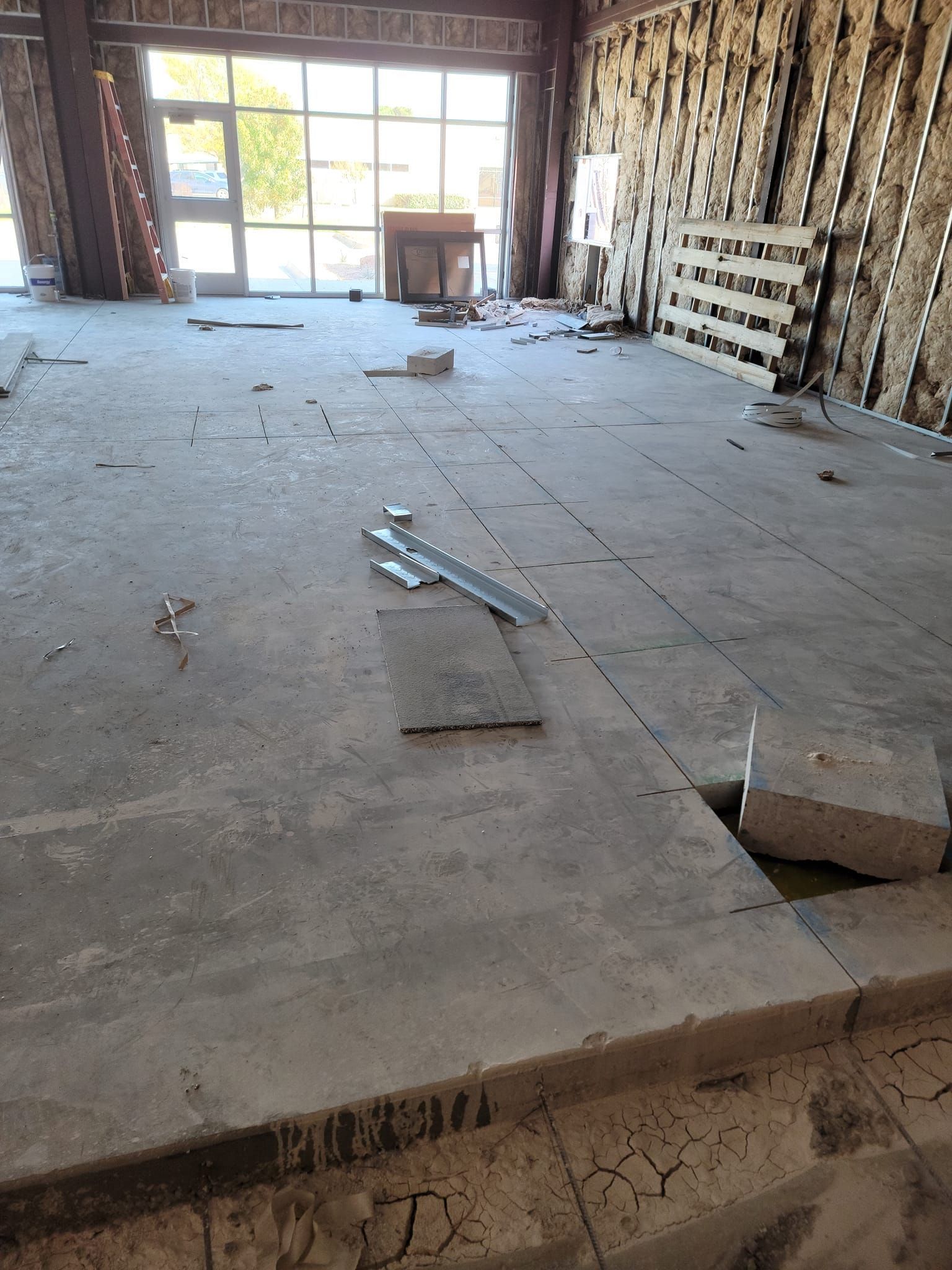 Empty unfinished room with a rough concrete floor, exposed walls, and a bright window at the far end.
