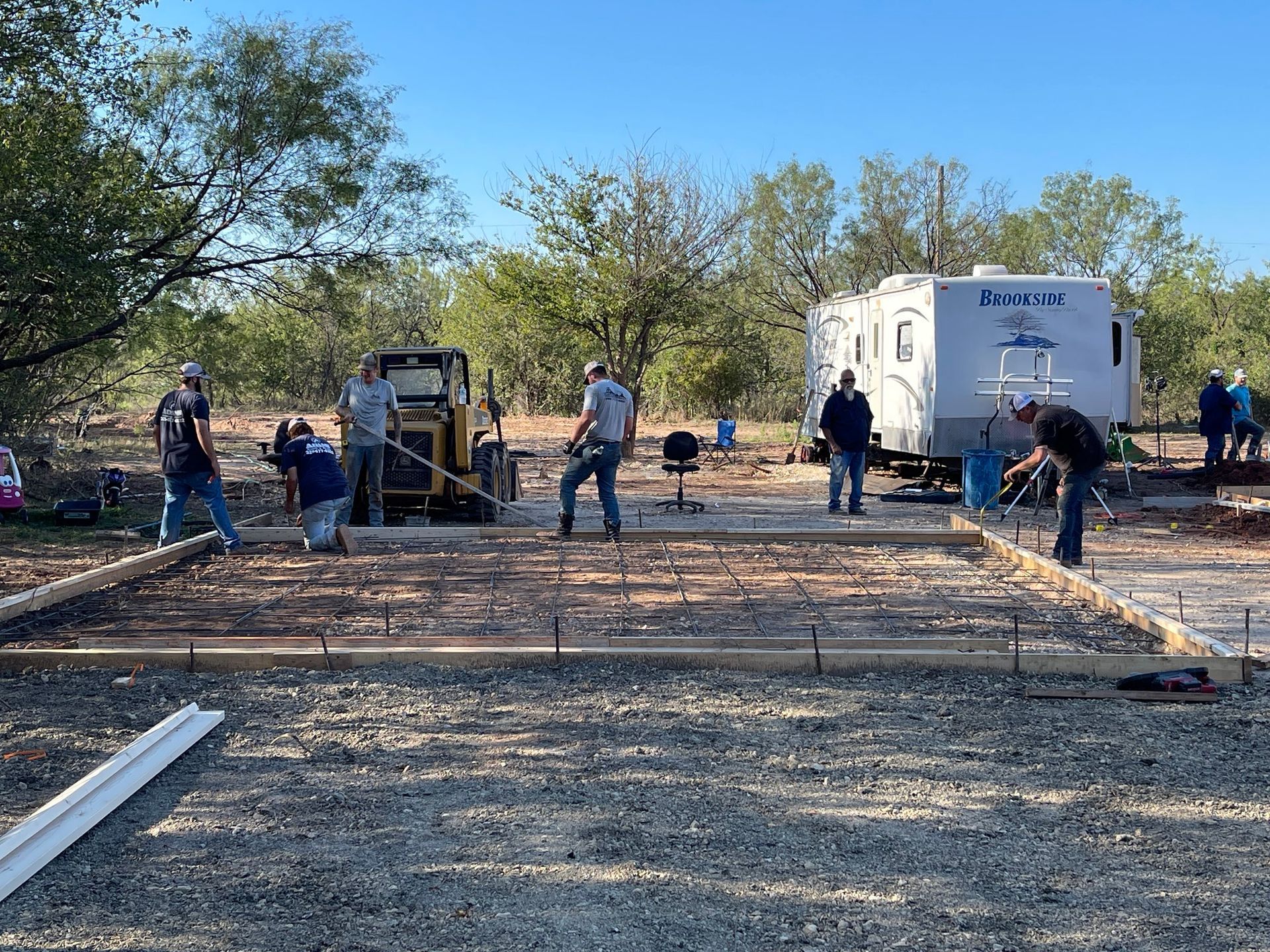 Construction workers pouring concrete for a foundation at an outdoor site with a trailer in the background
