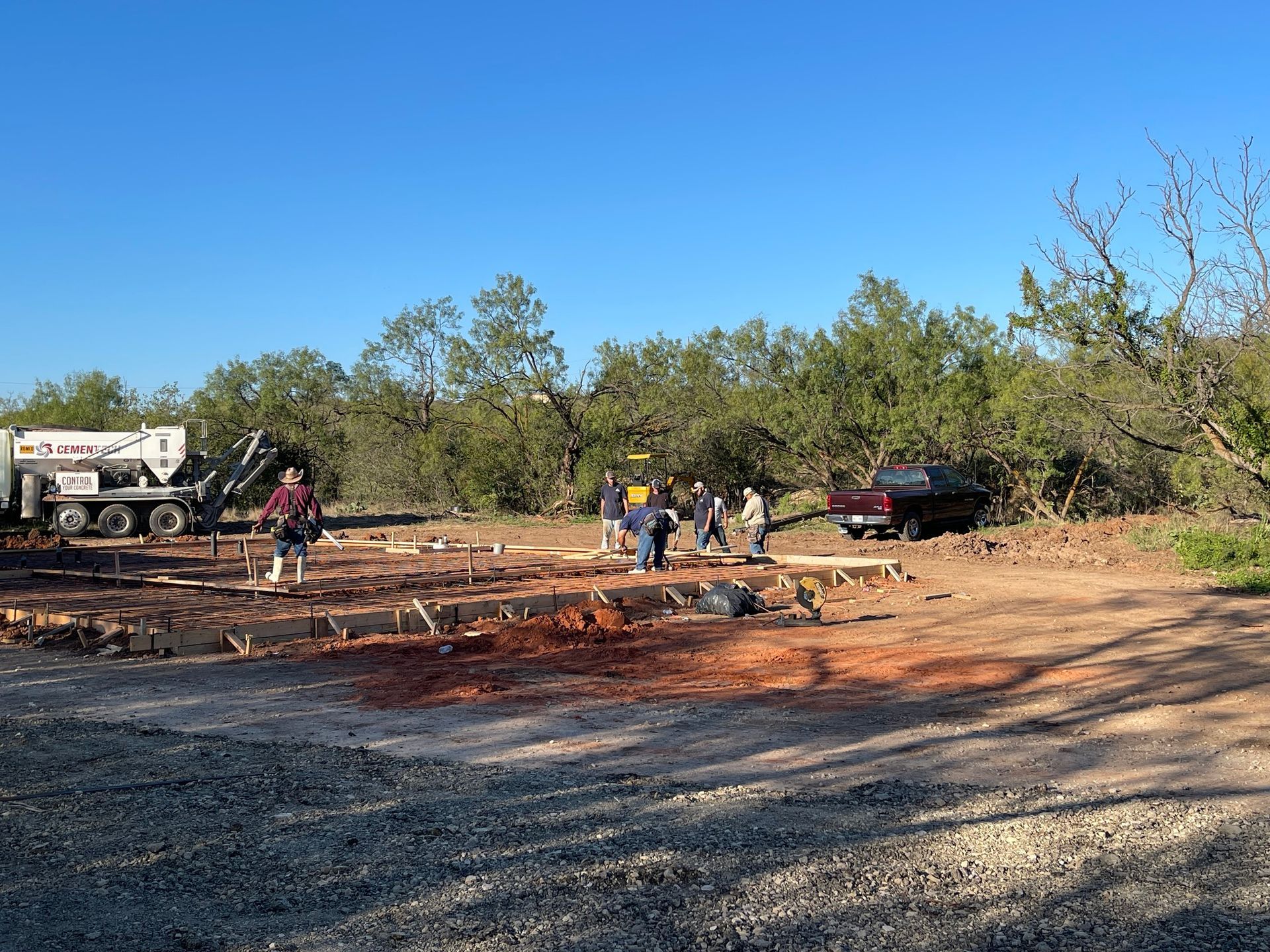 Workers and vehicles at a charred outdoor site under a clear blue sky