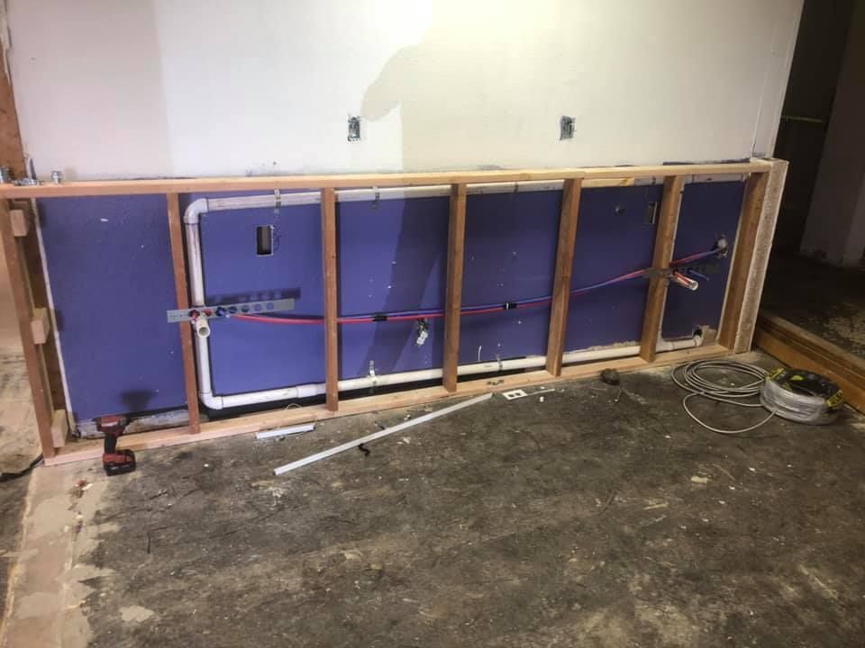 Partially dismantled wall with exposed wooden framing and purple insulation panels in an unfinished room