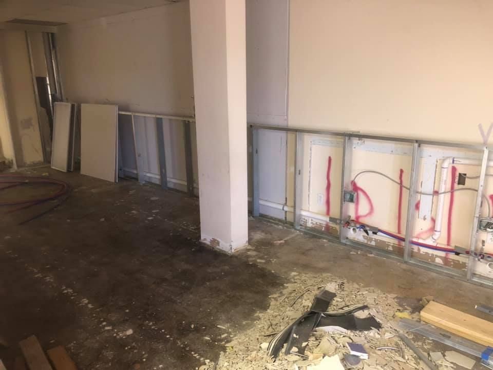 Unfinished room with exposed wall framing, construction debris, and concrete floor