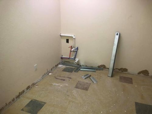 Bare room with unfinished floor, exposed plumbing, and a leaning white board against the wall
