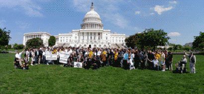 Group of people posing for a photo in front of the U.S. Capitol Building on a sunny day.