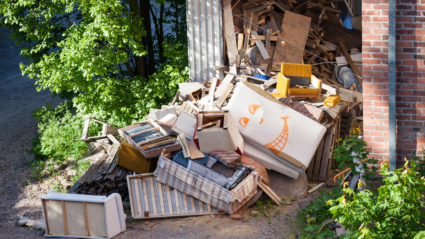 A pile of trash is sitting in front of a brick building for debris cleanup