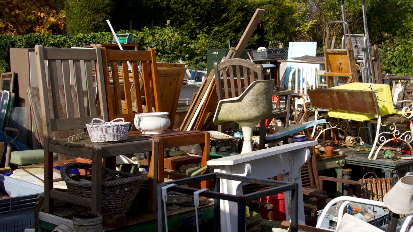 A pile of furniture is sitting on top of each other in a yard for debris removal