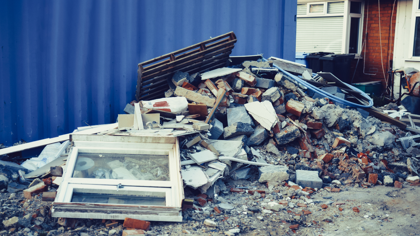 A pile of construction debris is sitting in front of a blue container.