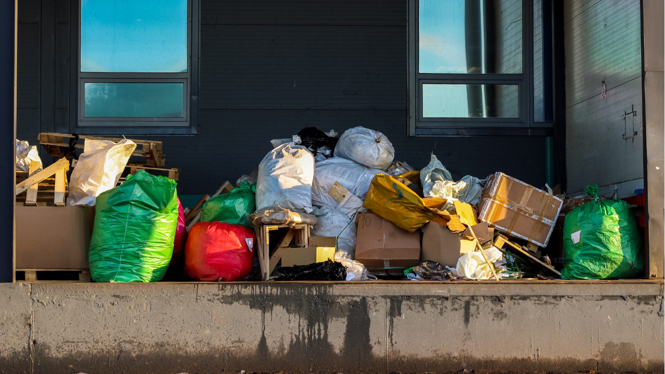 A dumpster trailer filled with trash bags is parked on the side of the road. - junk removal