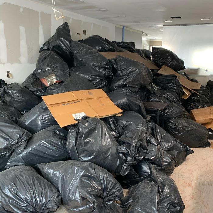 A pile of garbage bags and cardboard boxes in a room - junk removal