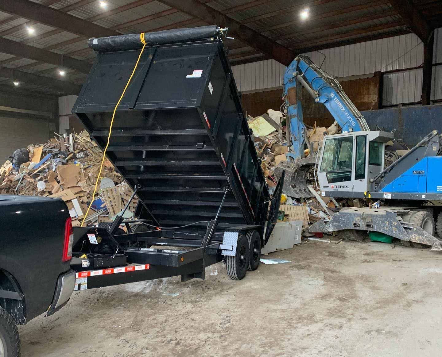 A dump truck is sitting in a warehouse next to a pile of trash.