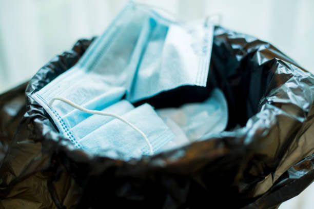 A pile of surgical masks in a trash can. - debris cleanup