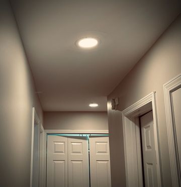 Hallway with recessed ceiling lights, white doors, and beige walls in a home interior