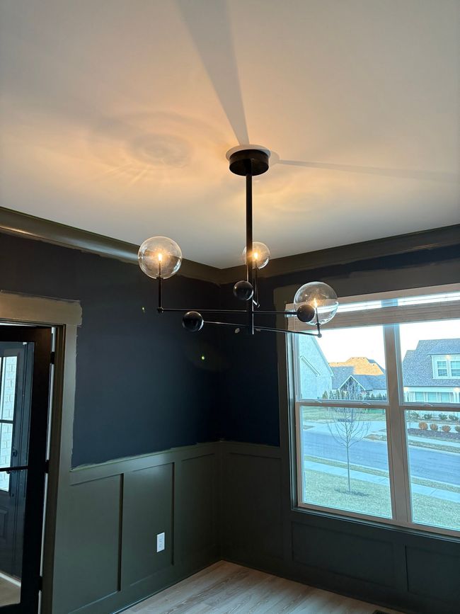 Modern room with dark walls, ceiling light fixture, and large window overlooking a snowy view