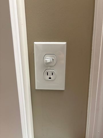 Wall plate with a switch and outlet on a beige wall near a white door frame