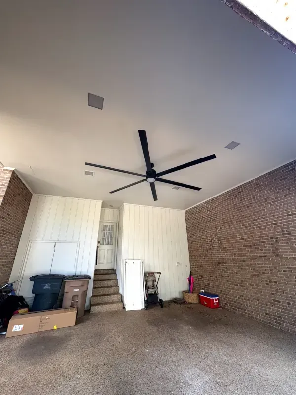 Covered patio with brick walls, ceiling fan, stairs, and stored items on the floor