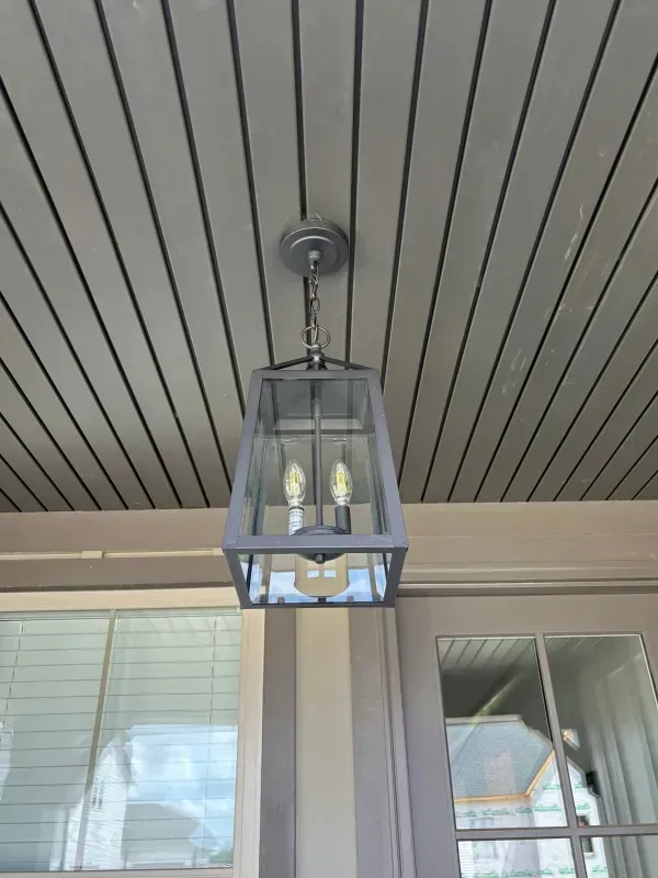 Black lantern-style porch light hanging under a striped ceiling above windows.