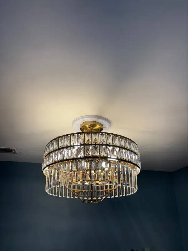 Crystal chandelier ceiling light in a room with a white ceiling and dark blue walls