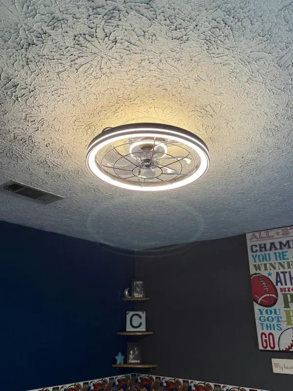 Bedroom ceiling with a lit ring light, dark blue walls, and wall decor visible below