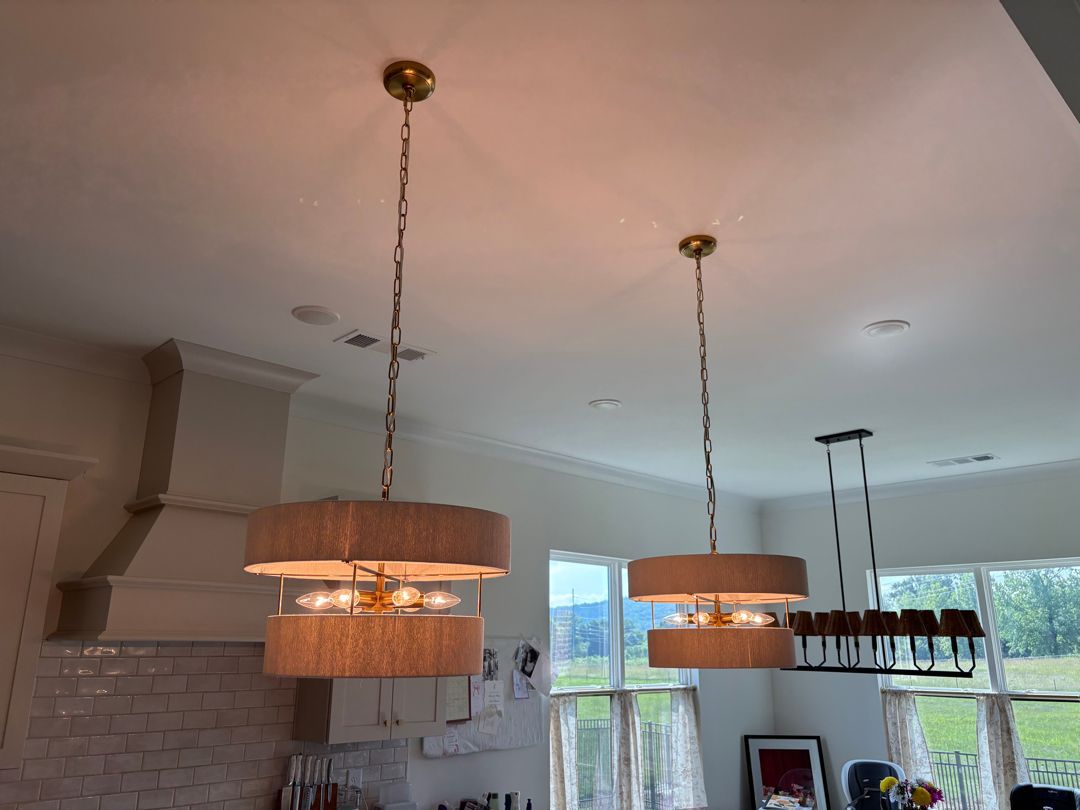 Modern kitchen with hanging pendant lights, white cabinets, and a window view