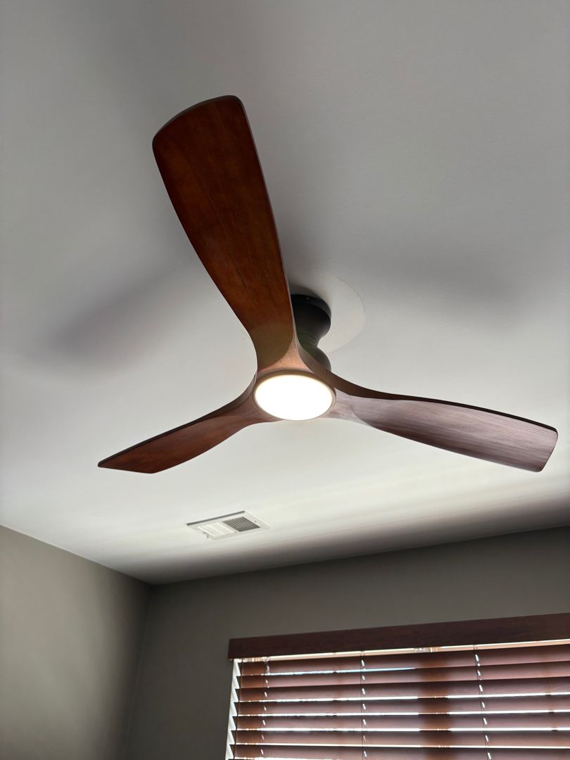 Ceiling fan with wooden blades and light in a room with a window and blinds