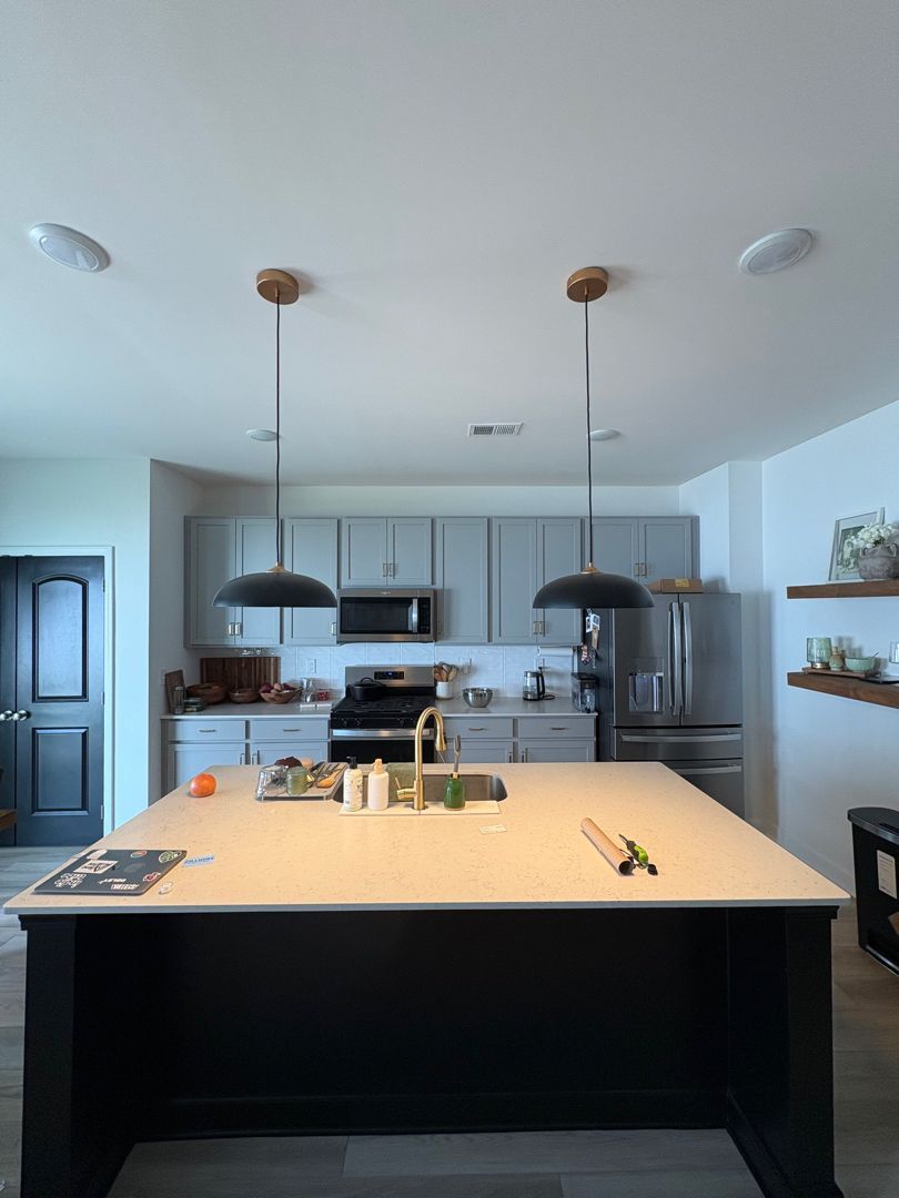 Modern kitchen with a large island, pendant lights, and gray cabinets in a bright open space
