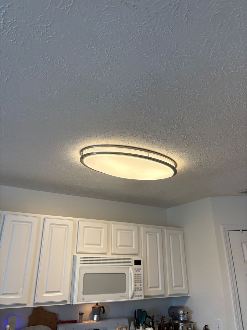 Kitchen ceiling light above white cabinets and a microwave