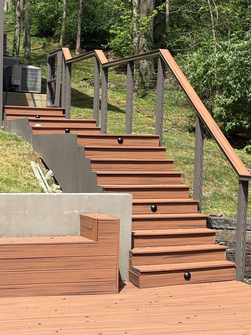 Wooden outdoor staircase with railings and concrete retaining walls in a wooded setting