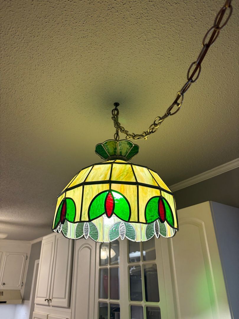 Stained-glass pendant lamp with green and red accents hanging in a kitchen ceiling