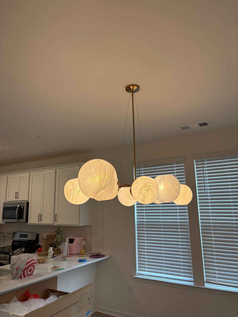 Modern kitchen with a lit globe pendant light over the island and window blinds in the background