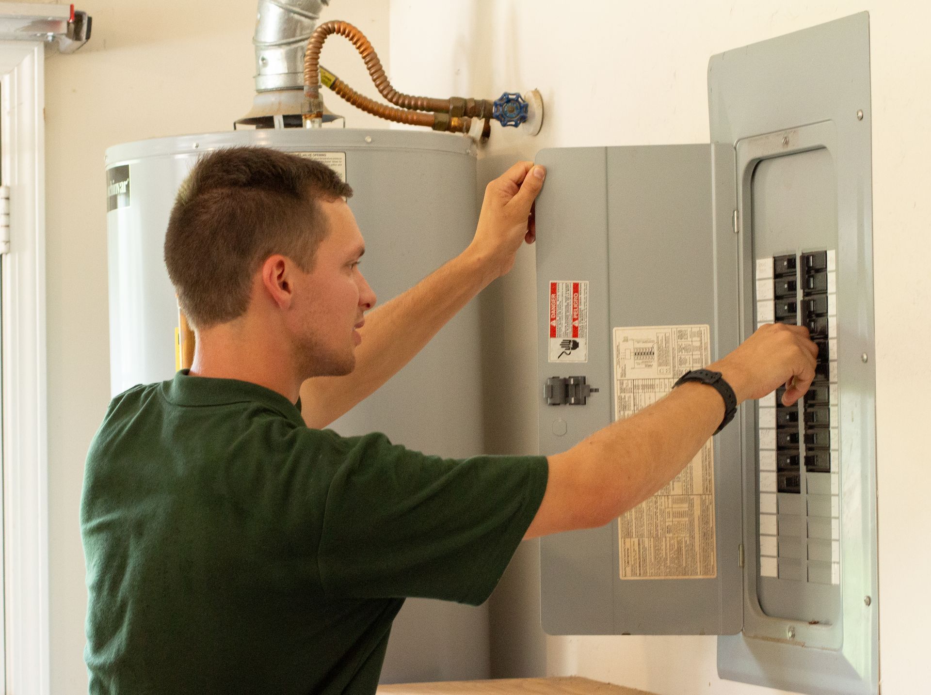 Man opening an electrical breaker panel in a utility room